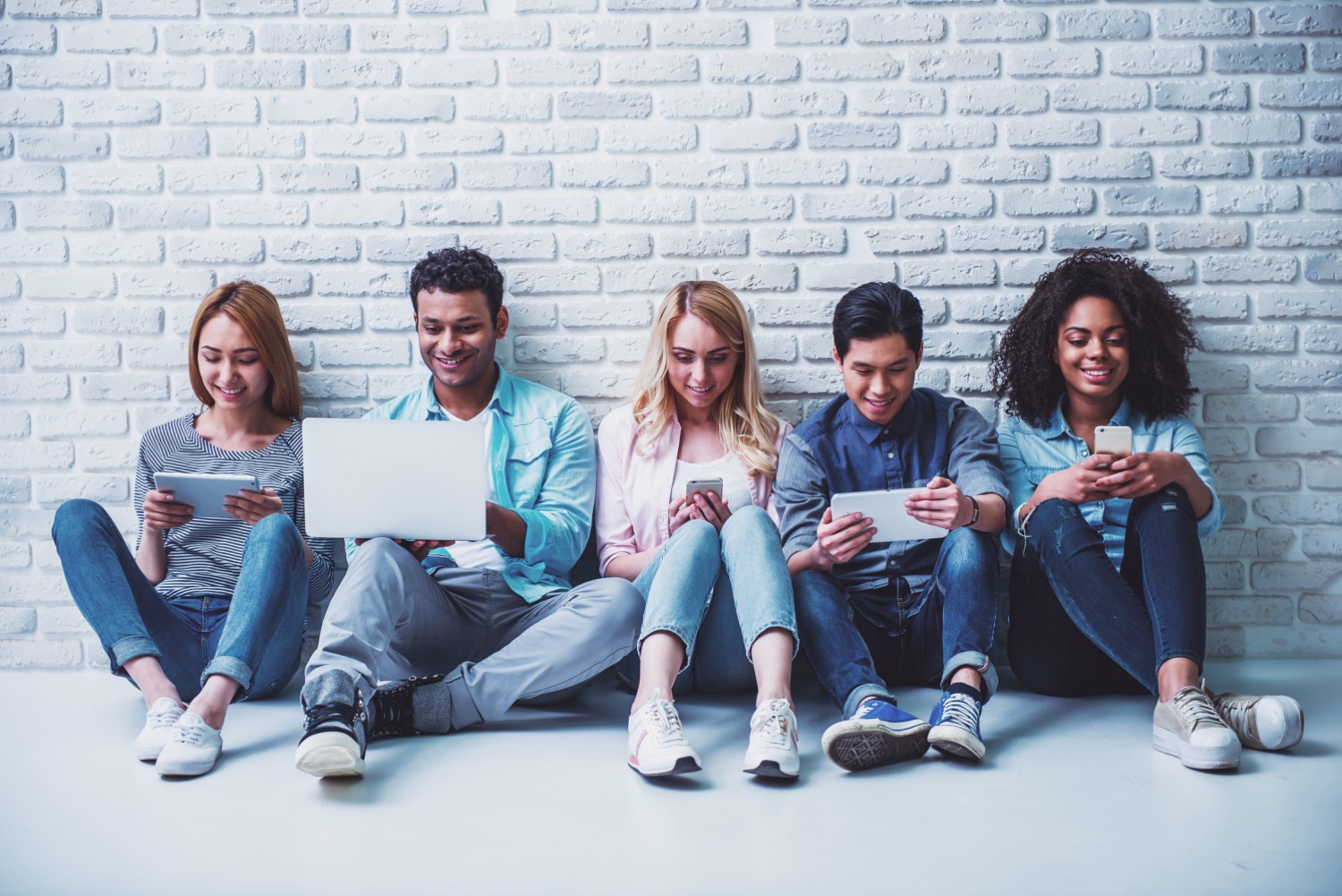A diverse group of people using laptops, tablets, and phones
