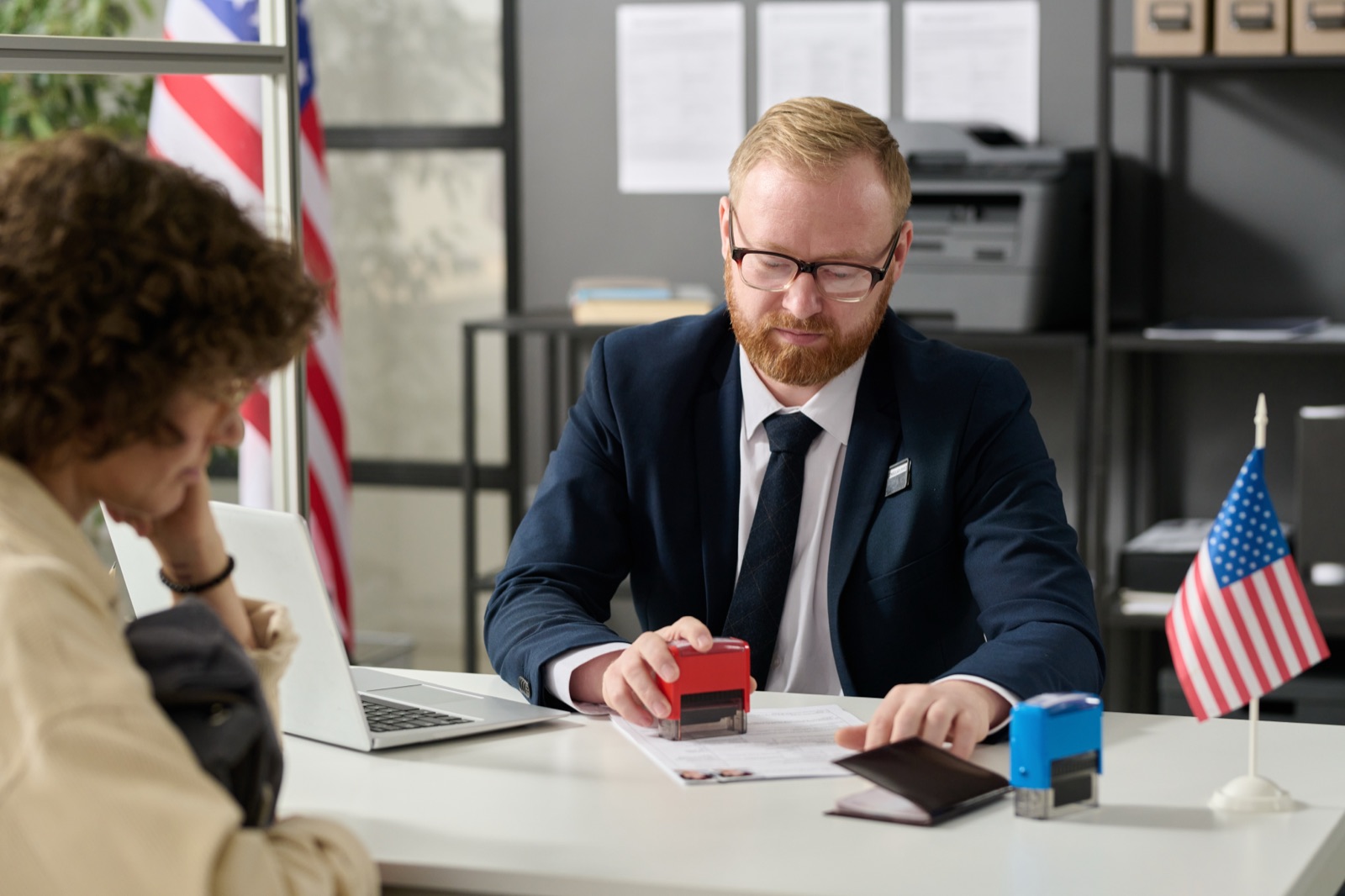 A government service desk where an official processes paperwork for a resident