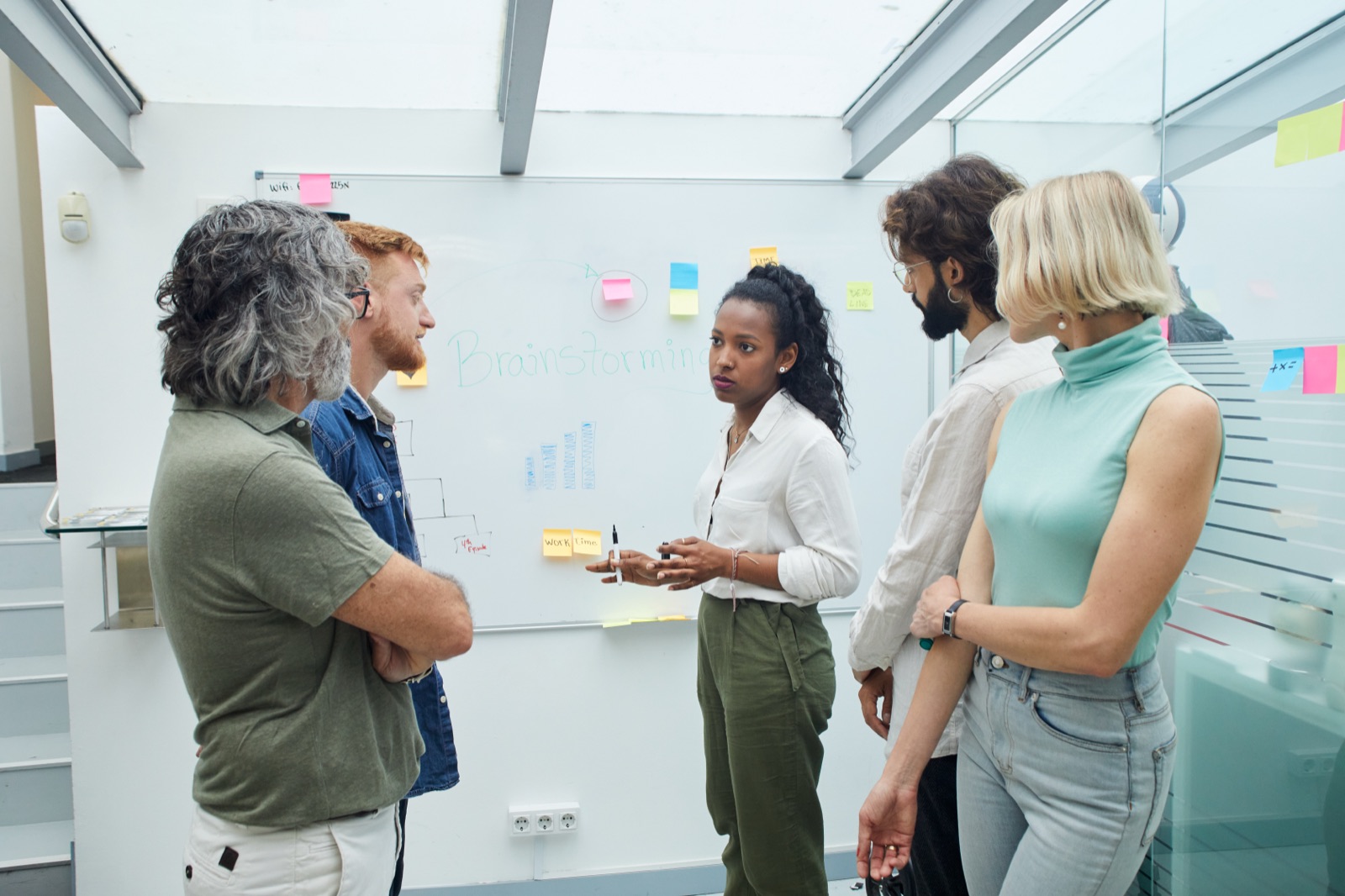 A small team mid-discussion at a whiteboard covered in sticky notes
